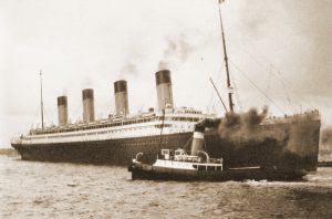A late-career photograph of Olympic with a tugboat.